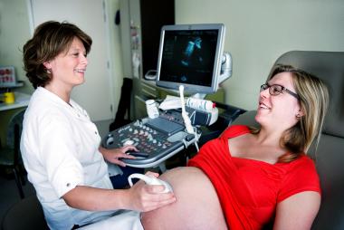 Een gynaecologe doet een echografie bij een hoogzwangere jonge vrouw