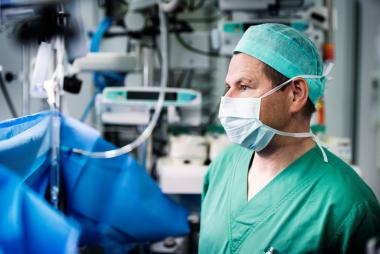 Een anesthesist met mondmasker volgt aandachtig een operatie