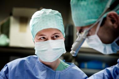 Verpleegkundige aan operatietafel naast arts die aan het opereren is