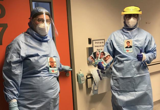 Twee verpleegkundigen in beschermingspakken met foto op borst