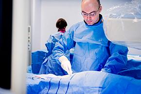 Foto van een hartspecialist bezig met het inbrengen van een catheter voor een hartonderzoek